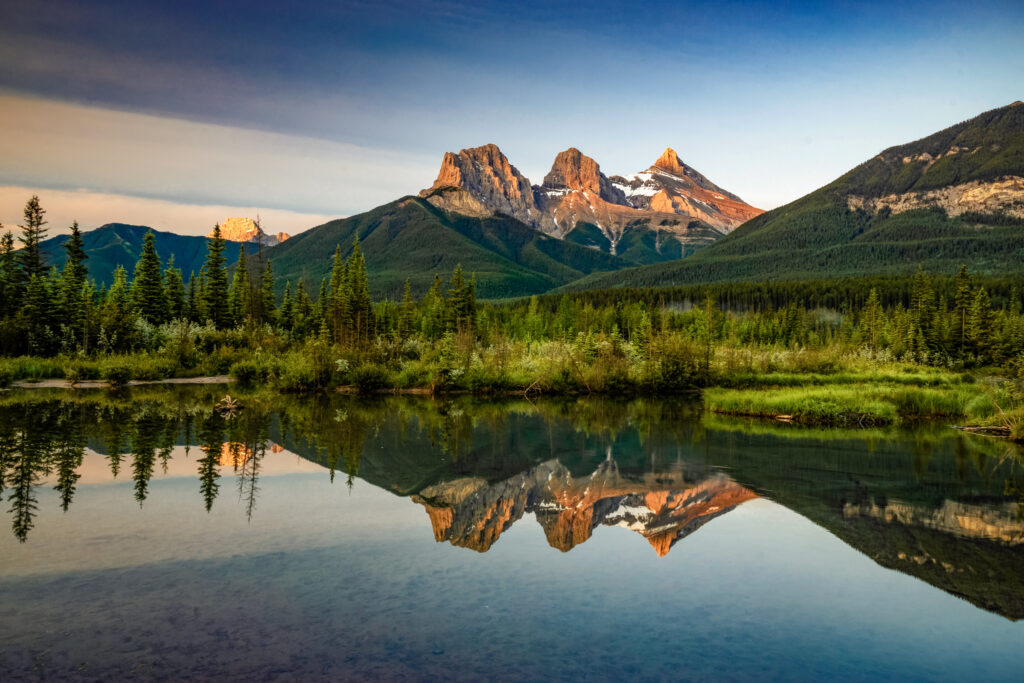 Sunrise with Three Sisters mountain reflection in calm waters of Policeman Creek, Canmore. Elope Canmore. Canmore Elopements. Banff Elopements.