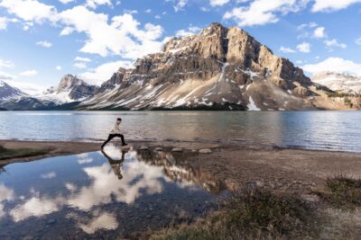 Photo of a guy jumping on the stepping stones at Bow Lake, Banff National Park. With a beautiful reflection in the water.