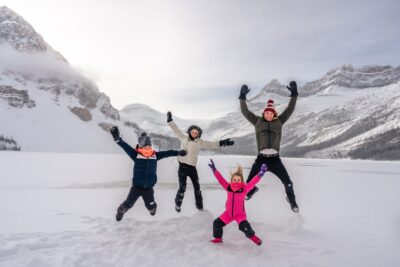 Photo of a family jumping in the snow at Bow Lake. Banff family photographer.