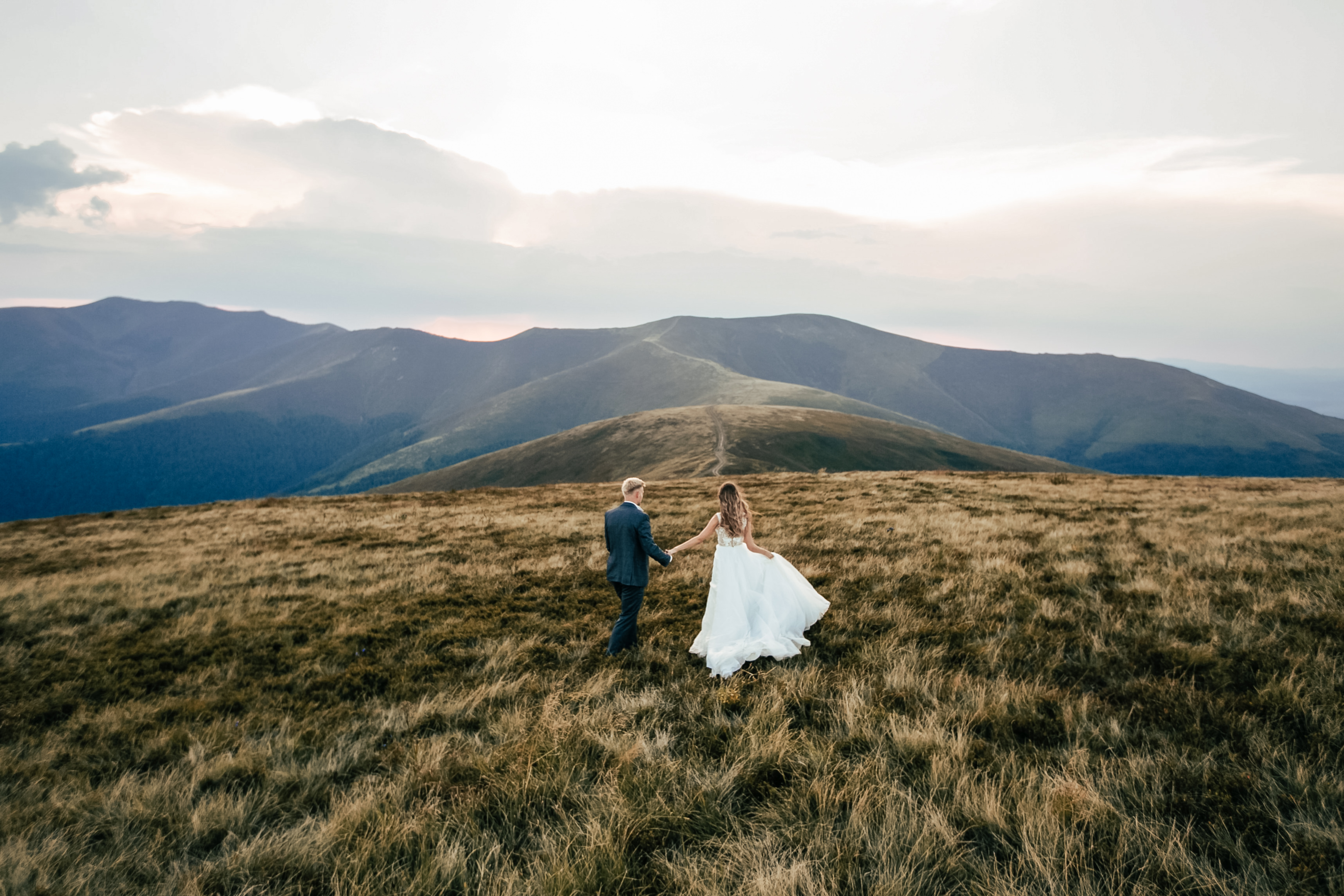 A couple standing on a mountain peak with a beautiful view, on a hiking adventure elopement